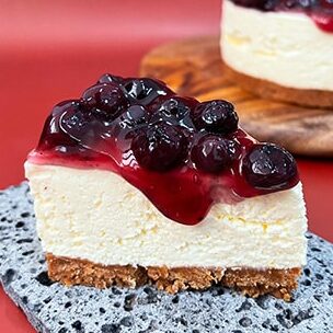 A slice of New-York cheesecake topped with blueberries