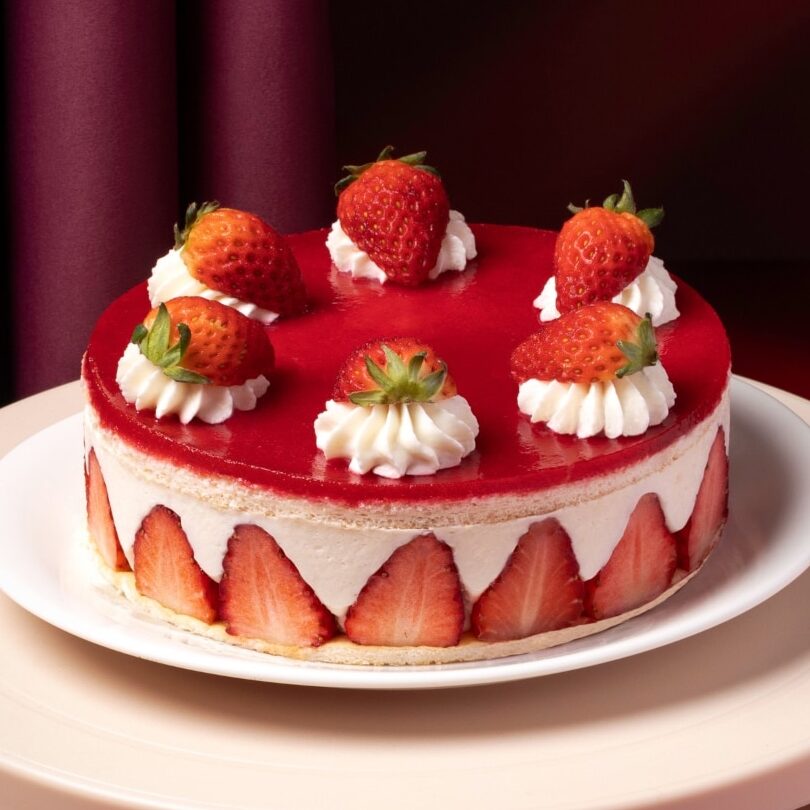 Close up of french strawberry cake with fresh strawberry on white plate.