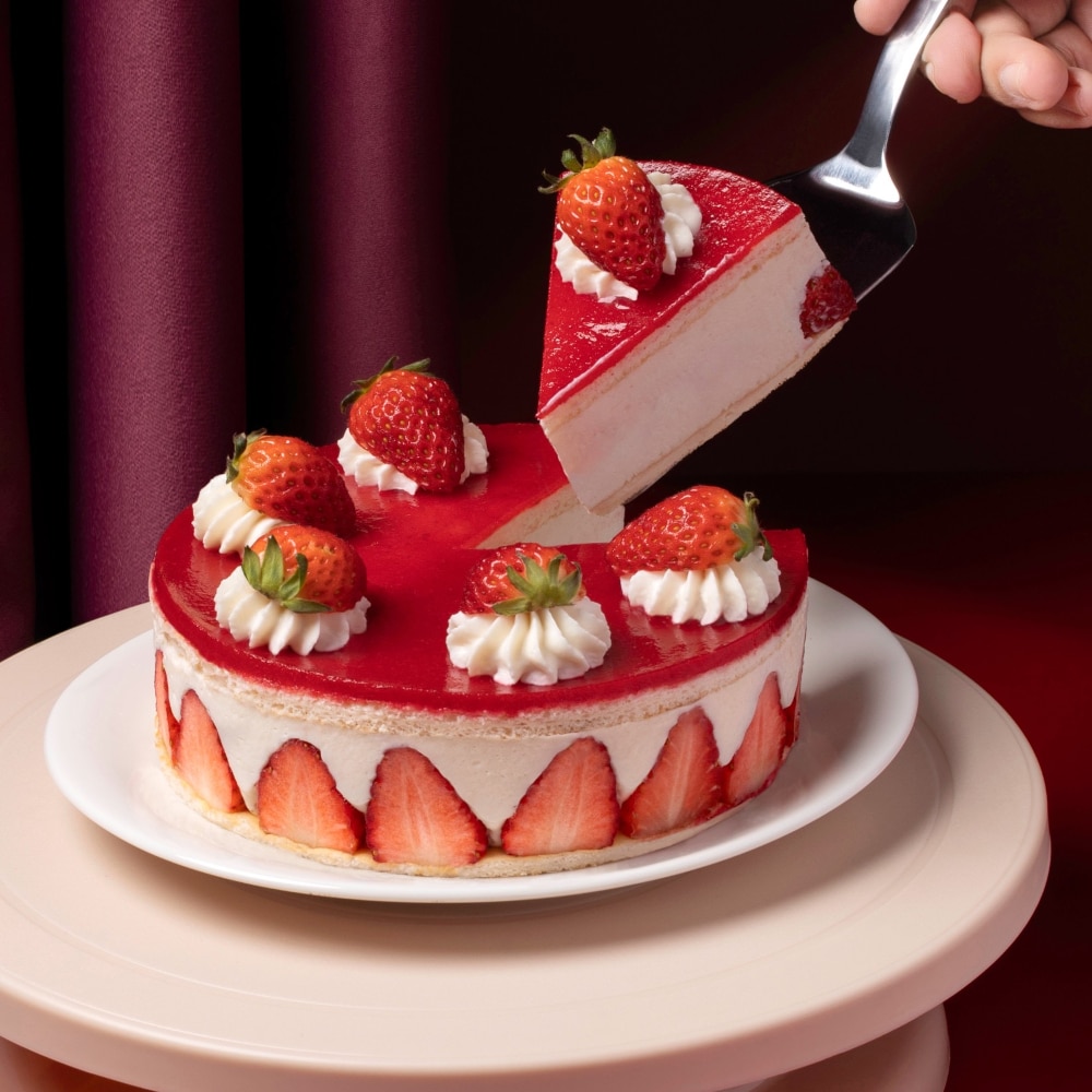 Sliced strawberry cake with fresh strawberry and mousseline cream on white plate in front of red background.