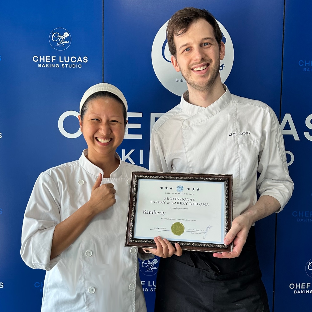 Female student and chef standing together, both smiling and holding a certificate. 