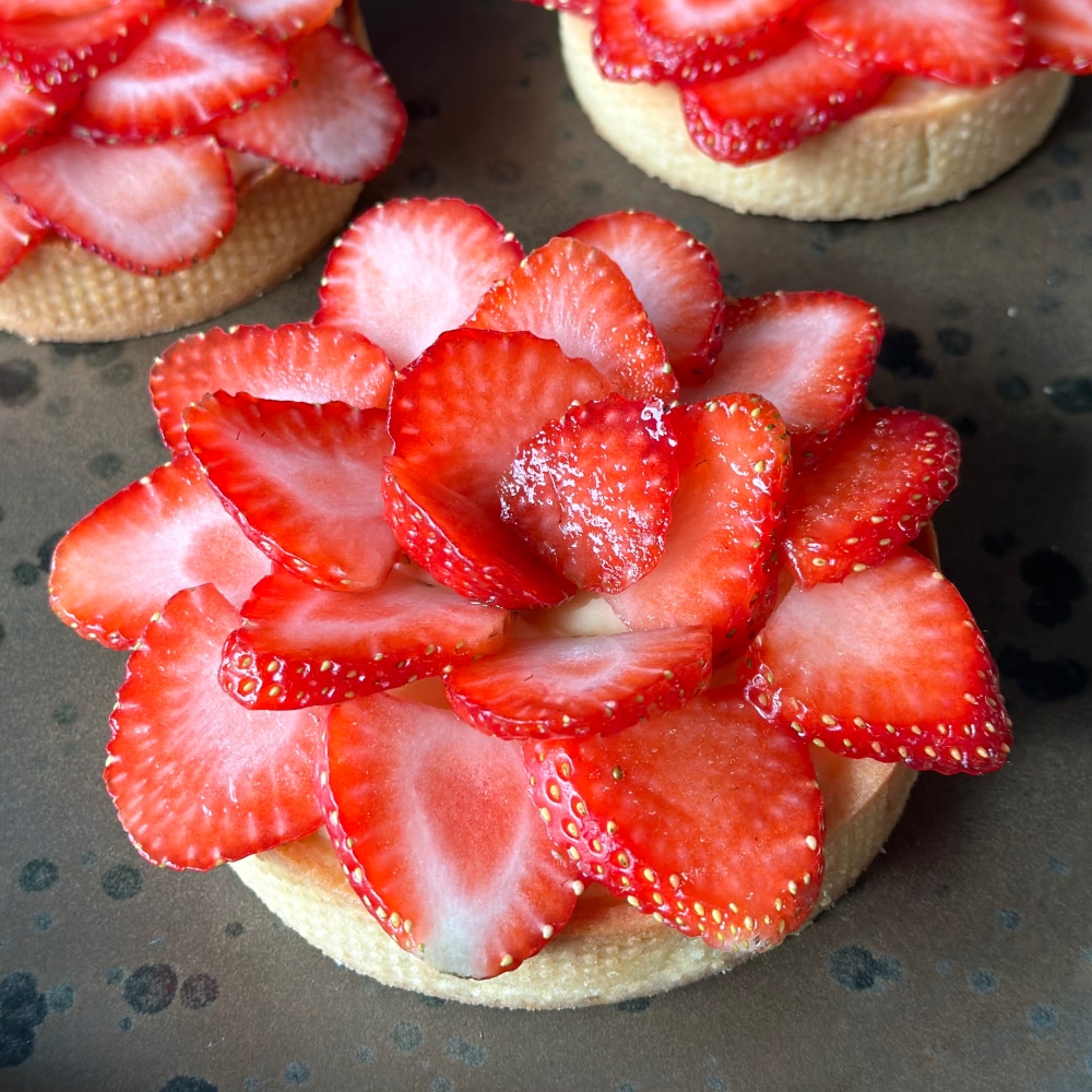 Strawberry tart with a crispy, golden pie crust filled with smooth pastry cream, topped with fresh, vibrant strawberries.